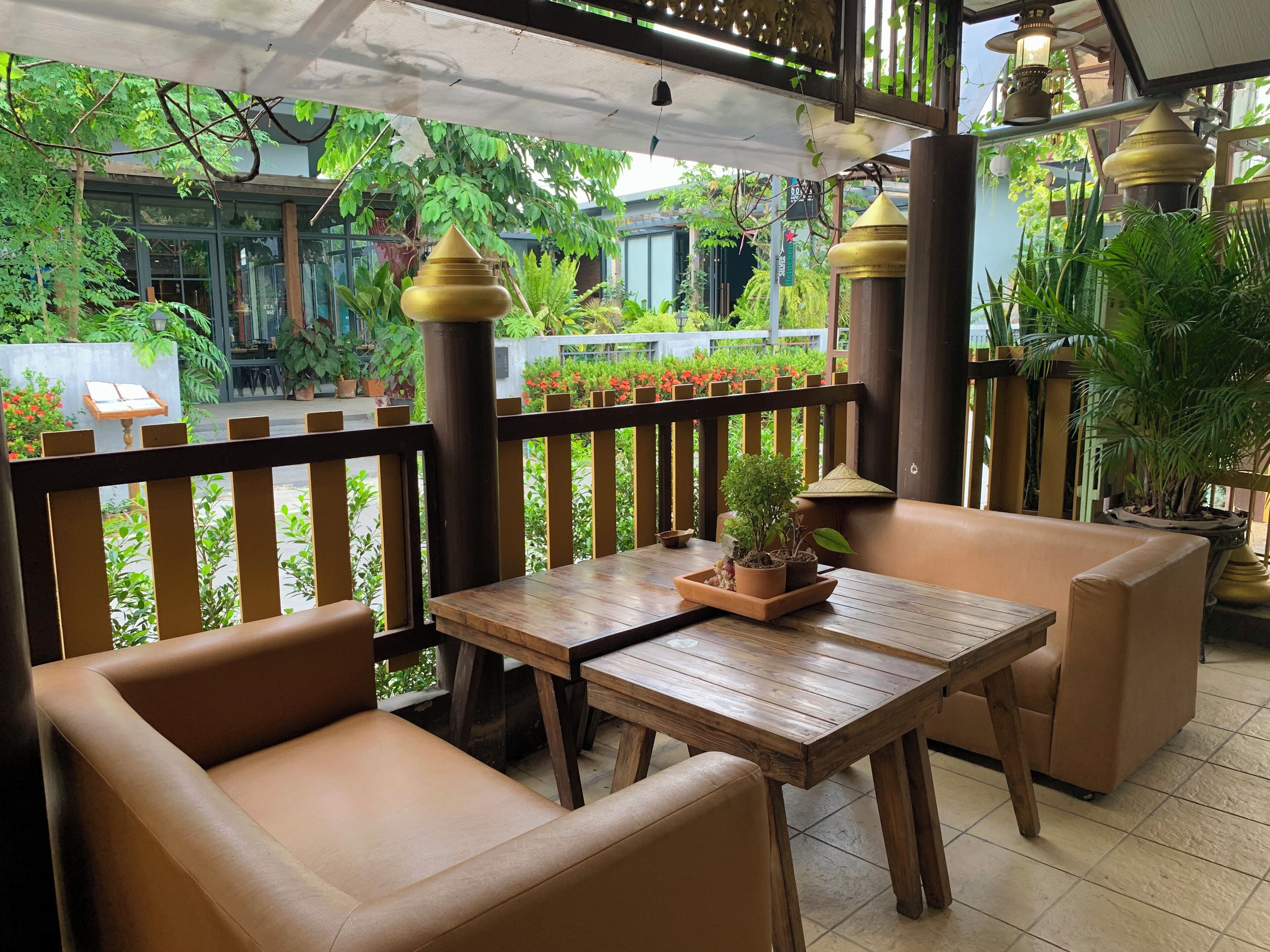 A wooden table with chairs and potted plants, surrounded by a wooden fence and greenery.