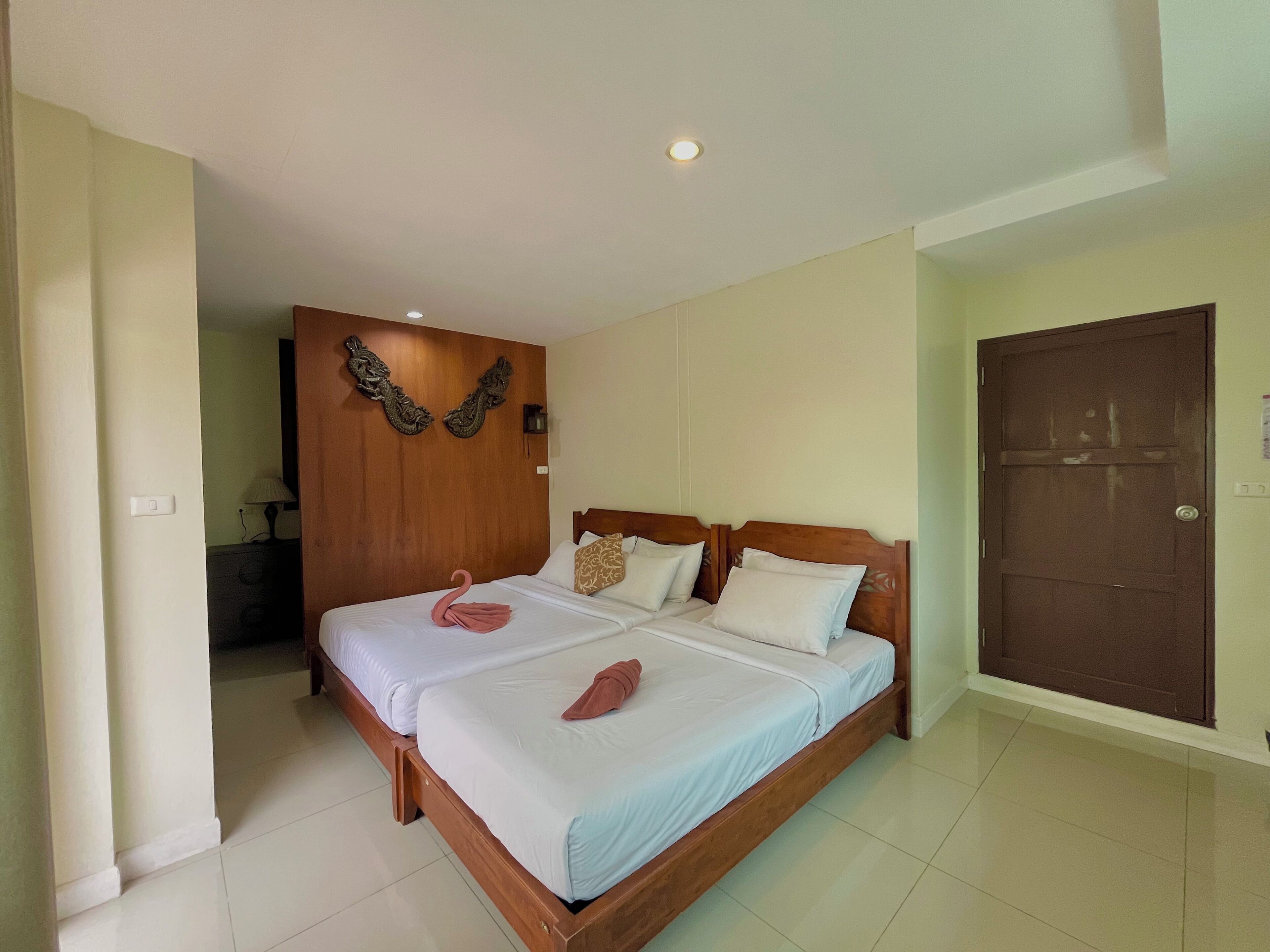 A double bed with a wooden headboard, two pillows, and a decorative swan towel.