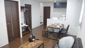 A modern living room with a wooden coffee table, a leather sofa, and a dining area with a table and chairs. - Nagayama Whole Apartment (Asahikawa)