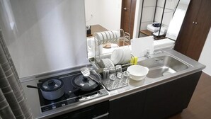 A compact kitchen with a stove, sink, and dish drying rack. - Nagayama Whole Apartment (Asahikawa)