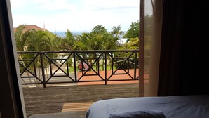 A room with a bed, a view of the outdoors through a window, and a wooden deck. - Fairview Bed And Breakfast - Double Bedroom 4 (Umhlanga)