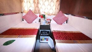 A room with two beds, each with a red and white patterned pillow, a small table with a vase of flowers, and a red and white patterned rug. - Standard Twin Room Ts (Kowloon)