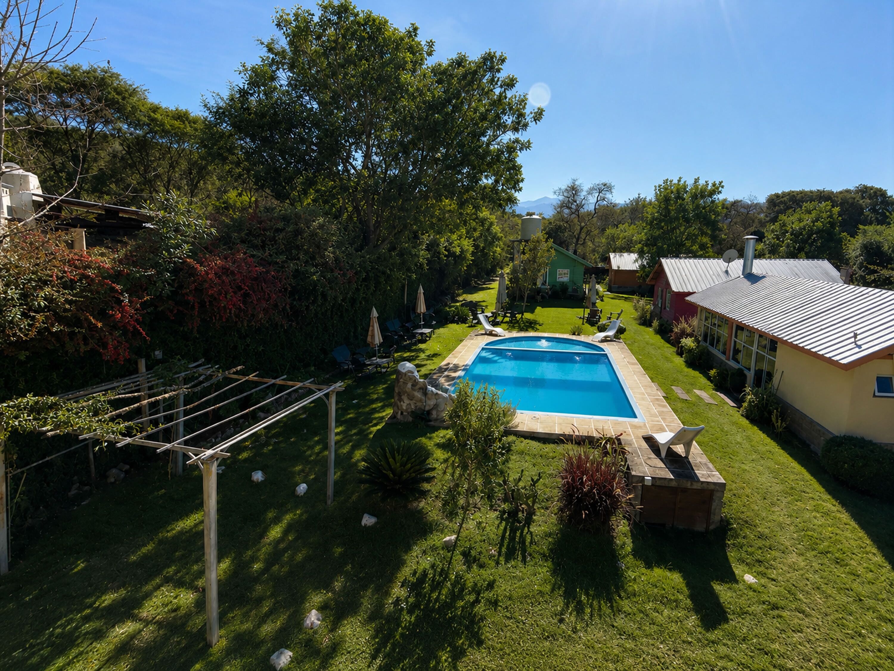A swimming pool surrounded by a well-maintained lawn, with a house in the background.