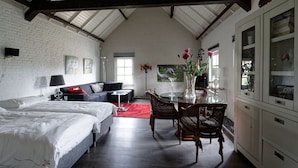 A spacious room with a high ceiling, a bed, a sofa, a dining table with chairs, and a kitchen area. - Room-room to Rent With own Entrance, liv (Blitterswijck)