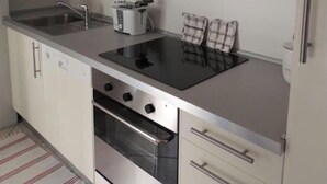 Une cuisine moderne avec des armoires blanches, une cuisinière en acier inoxydable et un pare-feu en verre.