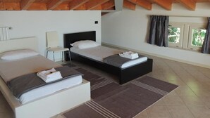 Une chambre avec deux lits, une table de chevet, une lampe et une fenêtre avec des rideaux.