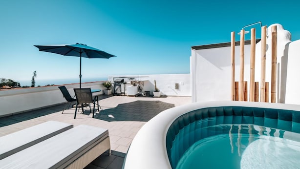 A rooftop pool with lounge chairs and a table, surrounded by potted plants and a clear blue sky. - Eternal Spring Free Wi Fi (Adeje)