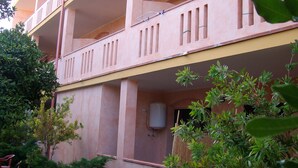 A multi-story building with balconies, a water tank, and surrounding greenery. - S'olivariu Village Guest House Swimming Pools Heart Of Sulcis (Piscinas)