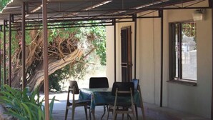 A covered outdoor seating area with a table and chairs, a tree, and a window. - Room-comfy Room With Dstv and Aircon in (Lephalale)