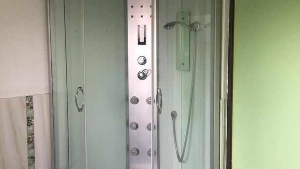 A corner shower enclosure with a glass door, a control panel, and a handheld showerhead. - Room in House - Patzerella's Cozy Nest (Krugersdorp)