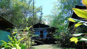 A rustic wooden structure with a thatched roof, surrounded by dense tropical vegetation. - Room-bungalow With sea View (Drake Bay)