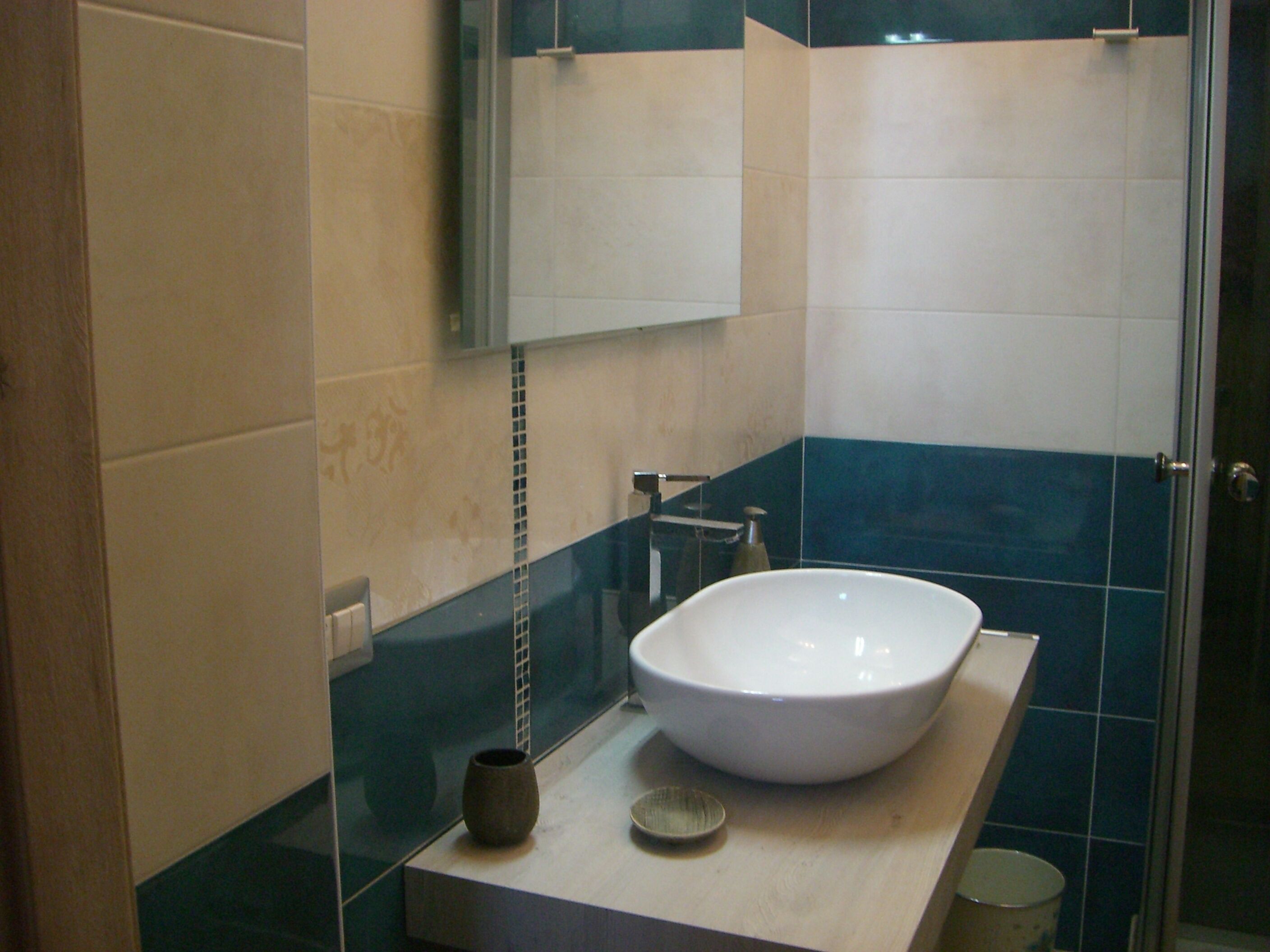 A bathroom with a large white sink, a small vase, and a mirror above it.