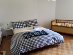 Une chambre à coucher avec une couvre-lit à carreaux, une petite table de chevet et une commode.
