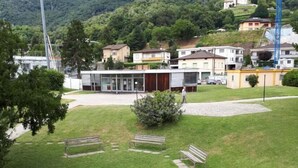 A grassy area with benches and a building with large windows. - Appartamenti La Bettola Chez Patty (Castel San Pietro)