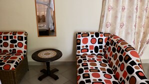 A room with two patterned sofas, a small round table, and a mirror on the wall.