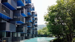 A modern hotel with a pool, surrounded by lush greenery and a mountainous backdrop. - Welcome to the Best and new Apartment to Have Great Trip in Patong Beach (Patong)