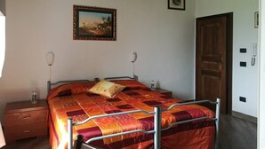 A bedroom with a bed, bedside tables, a nightstand, a door, and a wall-mounted picture. - Room in Holiday House - Double Twin Room With Balcony Pool View (Monte Castello di Vibio)