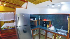 A compact kitchen with a refrigerator, microwave, coffee maker, and sink.