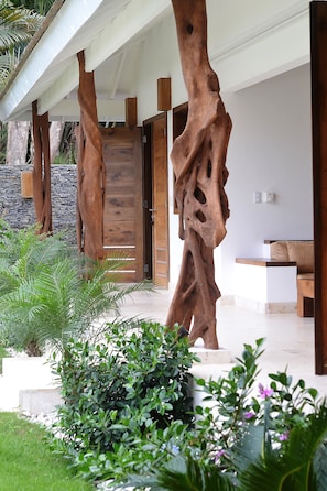 Relax in a serene outdoor space with a unique sculpture, entrance, and seating area surrounded by lush greenery.