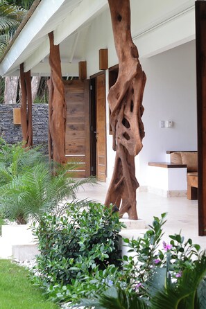 Un edificio moderno con una fachada de madera distintiva, un muro de piedra y un jardín cuidado.