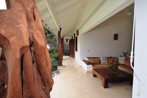 Un intérieur moderne agrémenté d’un tronc d’arbre en bois, un couloir menant à un espace détente avec un canapé et une table basse, ainsi qu’une petite plante en pot.