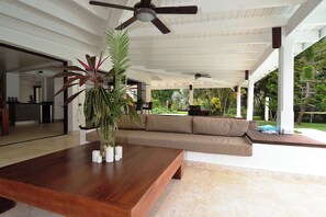 A spacious living area with a wooden coffee table, a beige sofa, and a ceiling fan.