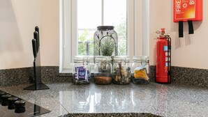 Un comptoir de cuisine avec une cuisinière à gaz, un extincteur et plusieurs bocaux en verre contenant divers objets.