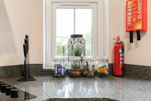 Kitchen features a granite countertop, a knife block, and storage for spices and tea.