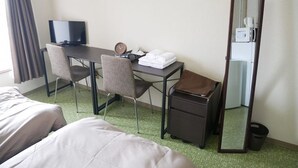 Ein Hotelzimmer mit Bett, Schreibtisch, Stuhl, Spiegel und einem kleinen Papierkorb.