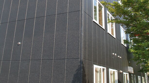 Ein Gebäude mit dunkler Fassade und zahlreichen Fenstern.