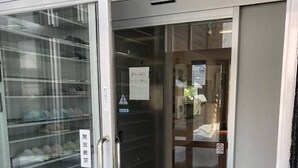 Ein Hotel Eingang mit Glastür, einem Schild, das eine Rauchfreie Zone kennzeichnet, und einem Paar Hausschuhe auf der Matte.