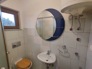Et badeværelse med toilet, vask og spejl.