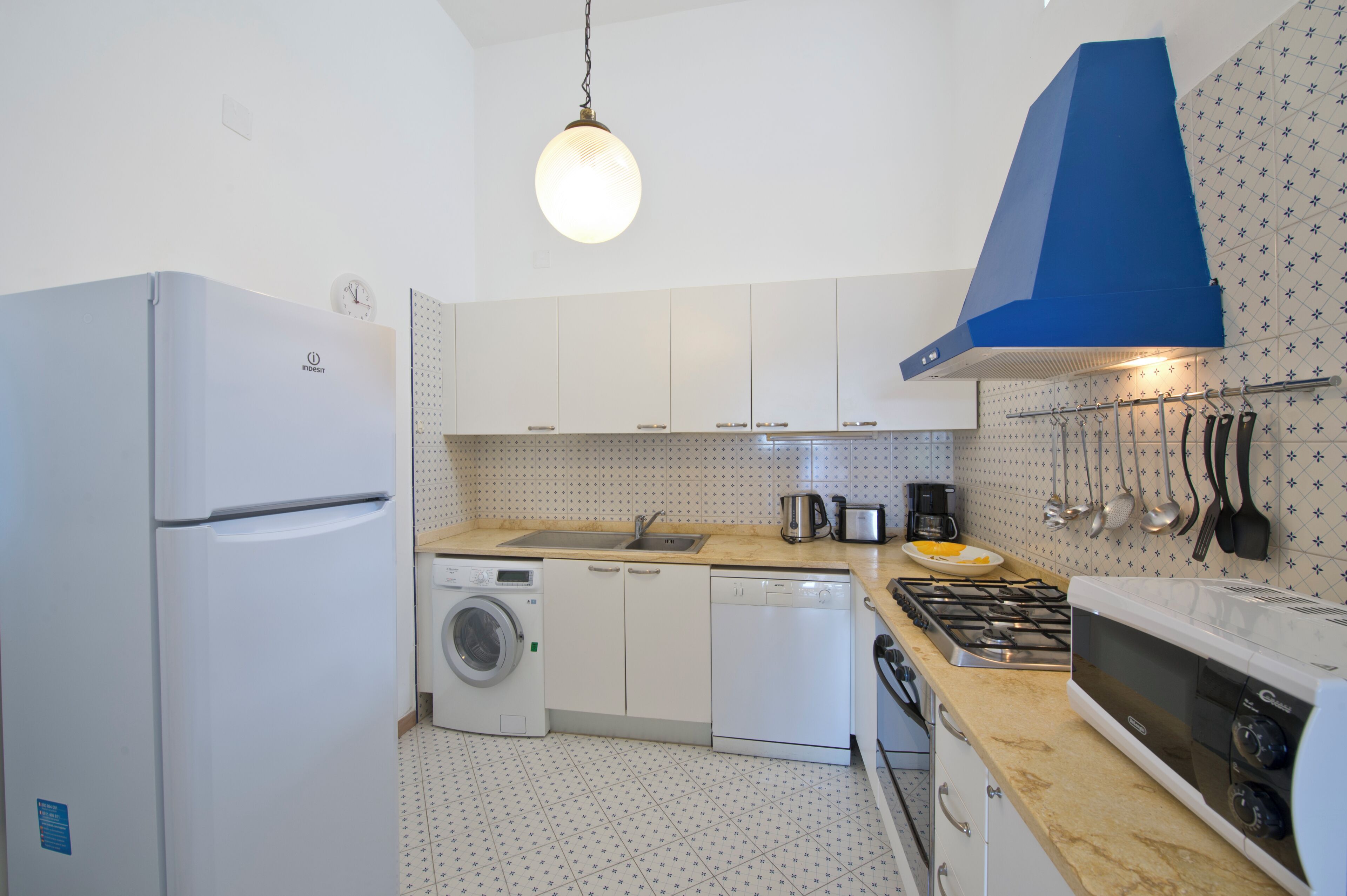 A compact kitchen with a refrigerator, washing machine, dishwasher, stove, and various utensils.