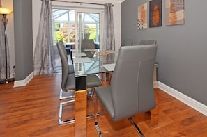 En matplats med ett bord i glas, grå stoppade stolar och utsikt genom stora fönster.