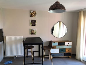 A room with a table, two stools, a mirror, a radiator, and a cabinet with drawers. - Amazing Studio In Lausanne Close To Epfl and Unil (Ecublens)