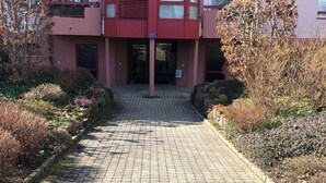 A multi-story building with a central entrance, surrounded by a paved walkway and various shrubs. - Amazing Studio In Lausanne Close To Epfl and Unil (Ecublens)