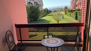 A balcony with two metal chairs and a small table, overlooking a well-maintained garden and distant buildings. - Amazing Studio In Lausanne Close To Epfl and Unil (Ecublens)