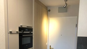 A narrow hallway with a built-in oven and a door with a gold handle. - Amazing Studio In Lausanne Close To Epfl and Unil (Ecublens)