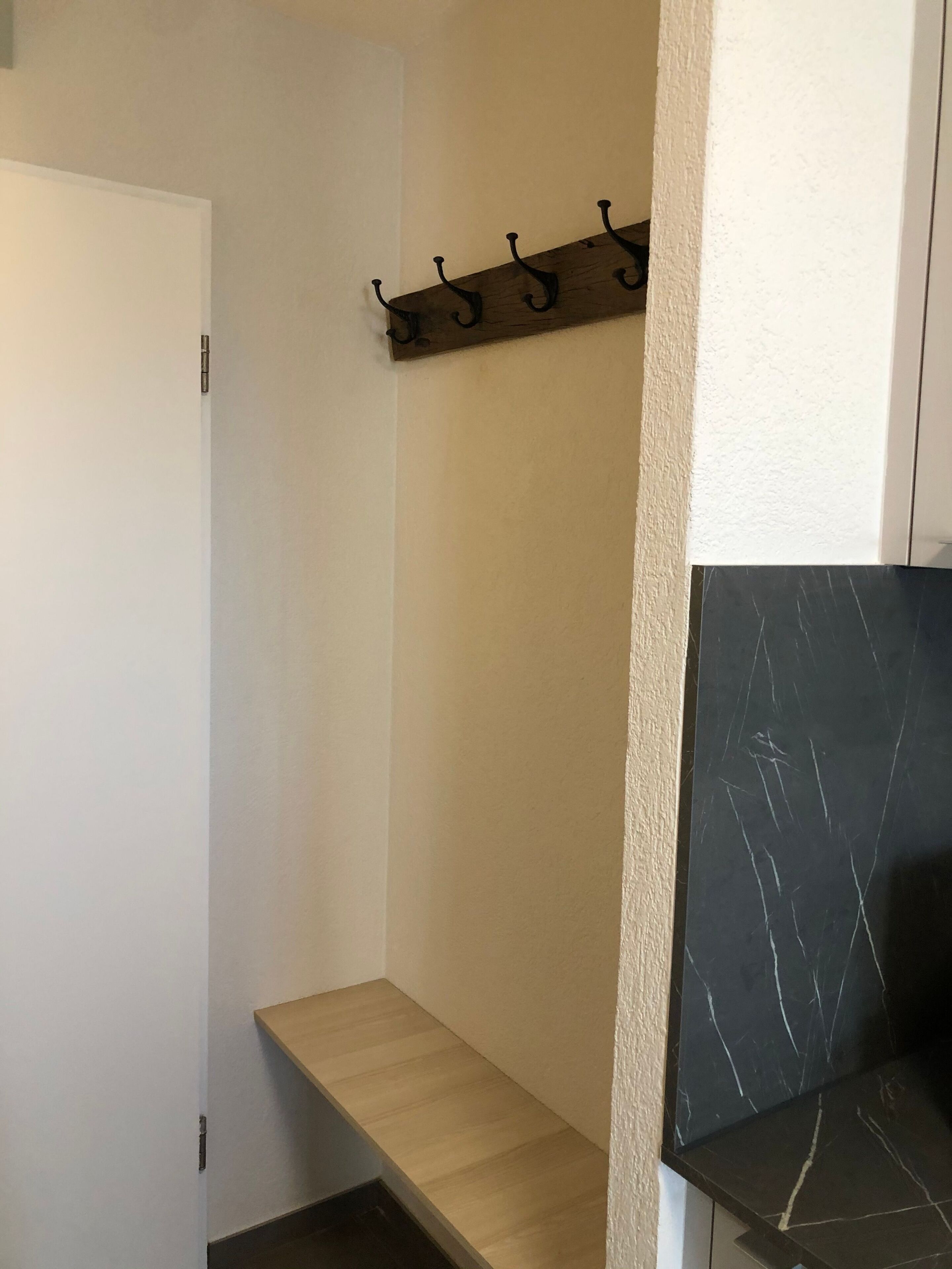 Un pasillo con un banco de madera, un perchero y una puerta.
