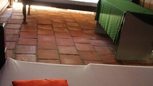 Una habitación con una cama, una mesa verde y suelo de ladrillo.