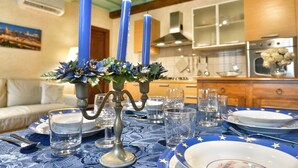 Een eettafel gedekt met een blauwe tafelkleed, borden en glazen, met een kaars als middelpunt.