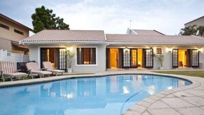 Une maison à deux étages avec une piscine, un patio couvert et un petit jardin.