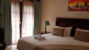 Une chambre d’hôtel avec un grand lit, un bureau, une lampe et un tableau au mur.