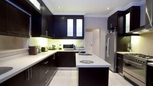 Une cuisine moderne avec des meubles de couleur sombre, un îlot central, un four à micro-ondes, un réfrigérateur et une cuisinière.