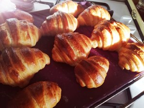 Une assiette remplie de croissants fraîchement sortis du four, posée sur une surface sombre.