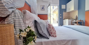 Une chambre d’hôtel avec un lit, des oreillers, un panier en osier et une vue sur l’extérieur.