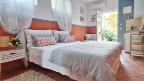 A bedroom with a bed, bedside tables, a window with curtains, a door leading outside, and a small table with a plant. - Studio Apartments Roza - A Charming Oasis in the Centre of Makarska (Makarska)
