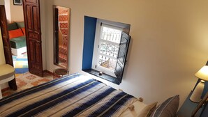 Makuuhuoneessa on sänky, ikkunassa metalliritilät, tuoli ja lamppuvarustettu pöytä.