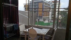 A balcony with a table and chairs, a drying rack, and a view of a building under construction. - 201 Jomtien Hill Resort Sudio (Pattaya)
