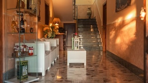 Un couloir avec une vitrine, des meubles en osier, une petite table sur laquelle est posée une lanterne, et un escalier.